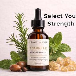 Puede incluir: Una botella de vidrio marrón de Heavenly Hair Anointed Hair Growth Oil con un cuentagotas, rodeada de ramitas de romero y menta, y una pila de resina de color ámbar. El texto "Select Your Strength" es visible. La botella contiene 60 ml.