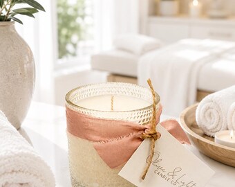 May include: A scented candle in a textured glass jar wrapped with a dusty rose ribbon and a square paper tag featuring the text Olive & Light Candle Co. The candle has a single wick and is filled with off-white wax, tied with a thin jute twine.