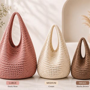 Può includere: Tre borse hobo all'uncinetto di diverse dimensioni e colori. La borsa grande è rosa antico, la borsa media è color crema e la borsa piccola è marrone moka. Ogni borsa presenta un manico integrato unico e un motivo a trama testurizzata.