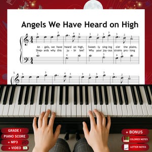 May include: A sheet music page titled Angels We Have Heard on High featuring black musical notation on a white background with numbered fingerings and lyrics, positioned above a black and white piano keyboard with hands playing.