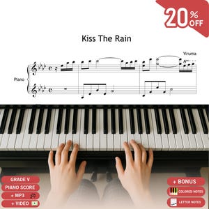 May include: A piano sheet music page titled Kiss The Rain by Yiruma, featuring musical notation on a staff. Below the score, a pair of hands is positioned over the black and white keys of a piano keyboard. Text labels indicate Grade V, piano score, MP3, video, colored notes, and letter notes.