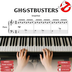 Könnte beinhalten: Ein vereinfachter Klavierauszug für "Ghostbusters". Das Bild zeigt eine Klaviatur mit Händen, die spielen. Text beinhaltet "Grade 1 Piano Score", "+ MP3" und "+ Video". Das Ghostbusters-Logo ist zu sehen.