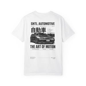 Könnte beinhalten: Ein weißes Kurzarm-T-Shirt mit einer schwarzen Grafik auf der Rückseite. Das Design zeigt eine detaillierte Illustration eines Sportwagens, japanische Kanji-Schriftzeichen und den Text SNTL AUTOMOTIVE, THE ART OF MOTION, ENGINEERING, SPEED, DESIGN.
