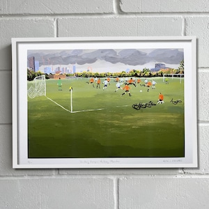 May include: A painting depicting a football match in progress on a green pitch. The players are wearing orange shirts and white shorts. There are several bicycles parked on the sidelines. The painting is titled "Sunday League at the Manor".