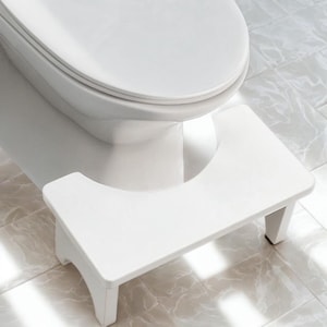 May include: A set of three ceramic mugs with a speckled, cream-colored glaze. Each mug features a different hand-painted design: a blue and green leaf, a yellow flower, and a red berry. The mugs have a simple, rounded shape.