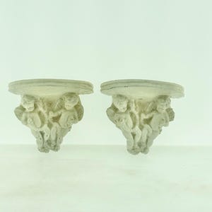 Puede incluir: Una taza de cerámica blanca con un asa negra y el texto "But First, Coffee" en negrita negra. La taza se encuentra sobre un fondo neutro, resaltando su diseño simple.