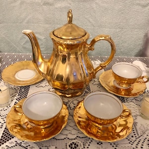 May include: A set of three ceramic mugs with a speckled, matte finish. The mugs are in shades of cream, light brown, and dark brown. Each mug has a simple, minimalist design and a rounded handle.