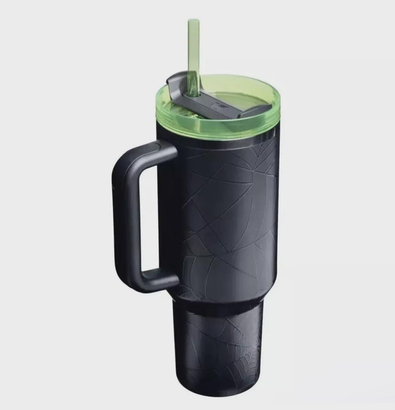Op de afbeelding: Zwarte ge&iuml;soleerde beker met een handvat, groene deksel en rietje. De beker heeft een getextureerd oppervlak met een geometrisch patroon. De beker is ontworpen voor ongeveer 887 ml.