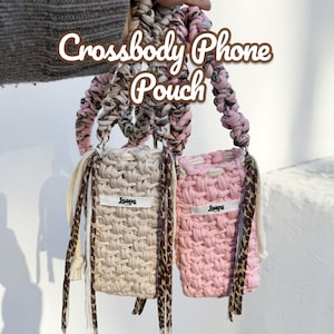 May include: Two rectangular crossbody phone pouches made of thick, braided fabric. One pouch is beige and the other is light pink. Each features a white label with the text 'Loops' and long, dangling fabric straps in leopard print and solid cream.