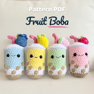 Könnte beinhalten: Vier gehäkelte Plüschtiere in Form von Boba-Tee-Getränken mit dem Text Pattern PDF Fruit Boba. Jedes hat eine andere Pastellfarbe, einen Fruchtaufsatz, einen rosa Strohhalm, schwarze Sicherheitsaugen und braune Boba-Perlen am Becherboden.