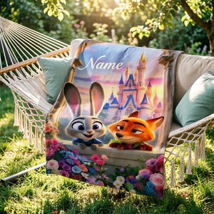 May include: A soft blanket displaying Judy Hopps and Nick Wilde from Zootopia, with a castle scene and the word "Name". The blanket is draped over a hammock, decorated with vibrant flowers.