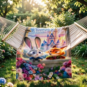 May include: A personalised blanket featuring Judy Hopps and Nick Wilde from Zootopia, with a castle backdrop and the word "Name" in script. The blanket is draped over a hammock, surrounded by colourful flowers.