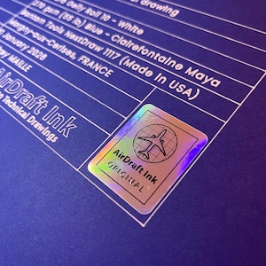 May include: A blue technical drawing with white text and a holographic sticker. The drawing includes details like paper type, weight, and the text "AirDraft Ink Original". The sticker features an airplane graphic.