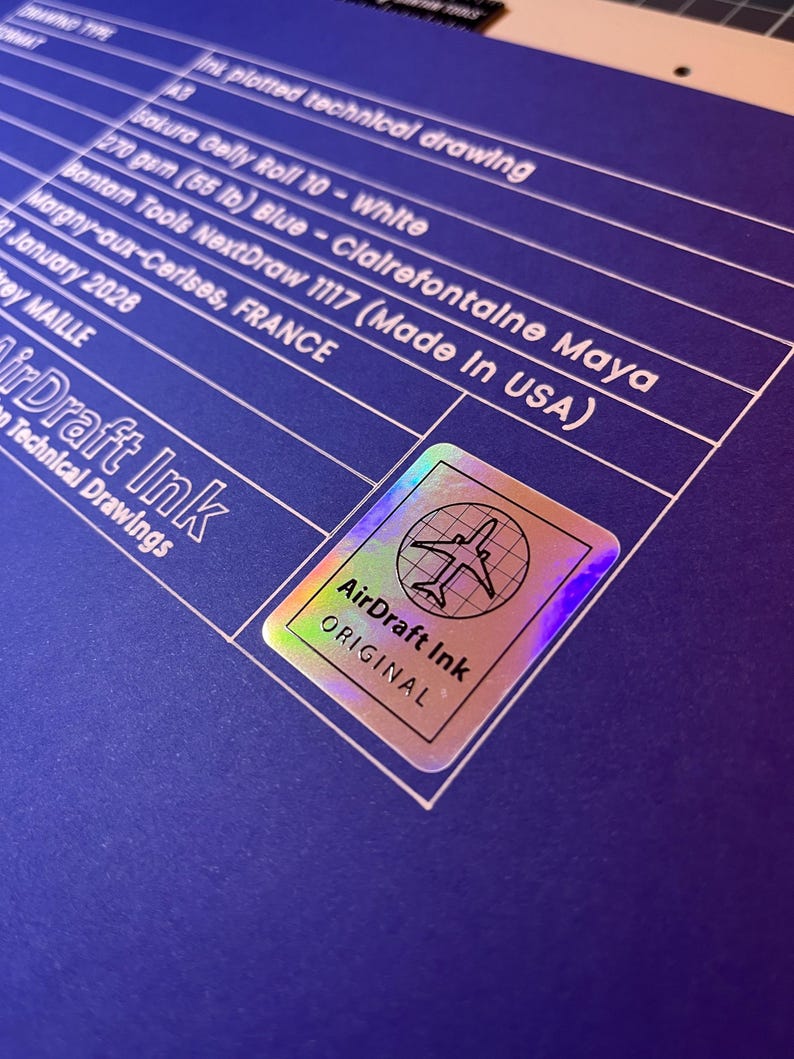 May include: A blue technical drawing with white text and a holographic sticker. The drawing includes details like paper type, weight, and the text "AirDraft Ink Original". The sticker features an airplane graphic.