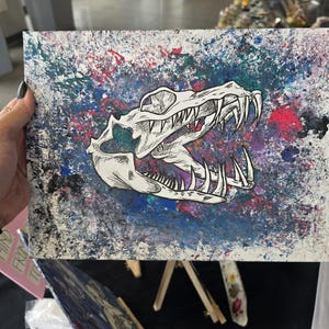 Può includere: Un dipinto su tela rettangolare che presenta un'illustrazione dettagliata a inchiostro nero e bianco di un teschio di rettile con denti affilati, centrato su uno sfondo vibrante e strutturato di vernice acrilica blu, rosa, viola e bianca.