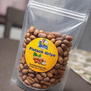 May include: A clear plastic bag filled with roasted peanuts. A yellow circular label reads "Pistach Griye" with a peanut graphic. The net weight is 6 oz (170 grams).