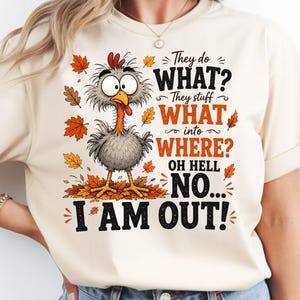 May include: A cream-coloured t-shirt featuring a cartoon turkey with wide eyes standing in autumn leaves. The text reads: They do WHAT? They stuff WHAT into WHERE? OH HELL NO... I AM OUT! The design includes orange and brown maple leaves.