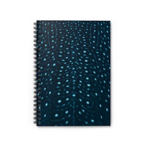 May include: A spiral-bound notebook with a dark blue cover featuring a pattern of small, light blue dots. The dots are arranged in a flowing, organic design. The notebook has a black metal spiral binding.