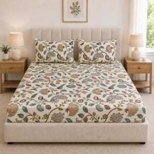 Könnte beinhalten: Ein Bett mit einem cremefarbenen Spannbettlaken und zwei passenden rechteckigen Kissen, die alle mit einem sich wiederholenden Blumen- und Paisley-Muster in Blaugrün, gedecktem Rot, Braun und Grün bedruckt sind, vor einem neutralen Polsterkopfteil.
