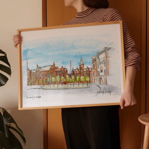 May include: A watercolor painting of a cityscape with a blue sky and white clouds. The buildings are red brick with white trim and there are trees in the foreground. The painting is signed "Jenny Pink" and titled "University of Liverpool".