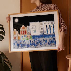Könnte beinhalten: Eine gerahmte Illustration einer Nachtszene mit einem Gebäude, auf dem "Welcome to Everton FC, Home of the Blues" steht. Das Gebäude ist beleuchtet und viele Menschen in blau-weißen Uniformen stehen davor.