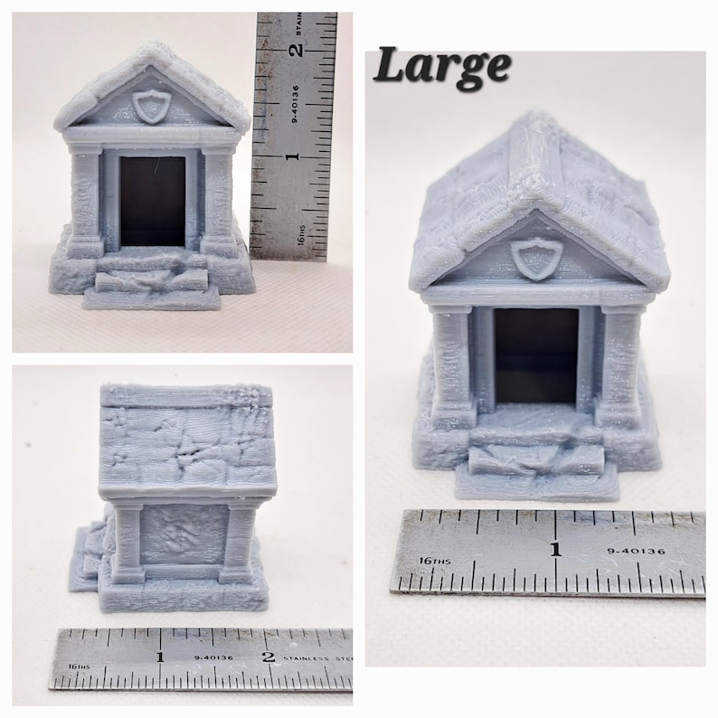 May include: A light gray miniature tomb with a shield emblem above the entrance. The model has a textured, stone-like appearance and is labeled "Large". A ruler is placed next to the model for scale.