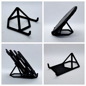 May include: Four different black plastic phone stands. The first stand is a triangular shape with a flat top. The second stand is a triangular shape with a curved top. The third stand is a triangular shape with a flat top and a stack of four plates on top. The fourth stand is a triangular shape with a flat top.