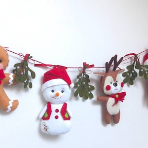 May include: A felt Christmas garland with a gingerbread person, snowman, reindeer, and Santa Claus. Each figure is decorated with red and white accents and is strung with green felt mistletoe.
