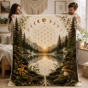 May include: A rectangular throw blanket featuring a detailed landscape print of a forest, a lake, and mountains at sunset. The design includes a golden flower of life pattern, moon phases, and various mushrooms in the foreground with mossy textures.