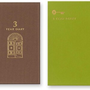 May include: Two hardback journals, one brown and one lime green, each featuring gold foil stamping. The brown journal displays a door illustration and the text 3 YEAR DIARY. The green journal features a key icon and the text 3 YEAR DIARY.