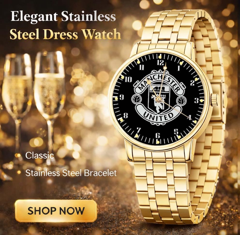 May include: A gold-toned stainless steel dress watch with a black face featuring the Manchester United logo. The watch has a matching gold bracelet and is displayed with champagne flutes. The text reads "Elegant Stainless Steel Dress Watch."