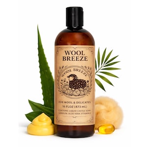 Könnte beinhalten: Eine braune Flasche Wool Breeze Flüssigseife für Wolle und Feinwäsche mit schwarzem Verschluss. Das Etikett zeigt eine Schafillustration. Das Bild enthält Aloe Vera, eine gelbe Seife und eine gelbe Kapsel.