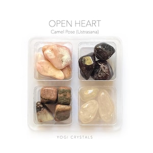 Könnte beinhalten: Ein Set Kristalle in einem durchsichtigen Plastikbehälter mit der Aufschrift "OPEN HEART Camel Pose (Ustrasana)" und "YOGI CRYSTALS". Die Kristalle sind rosa, braun, schwarz und klar.