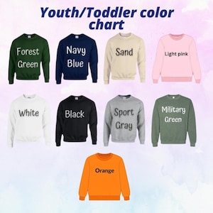 May include: A youth and toddler color chart featuring nine crewneck sweatshirts in forest green, navy blue, sand, light pink, white, black, sport gray, military green, and orange. Each sweatshirt is labeled with its corresponding color name.