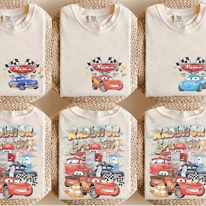 May include: Six cream-coloured t-shirts with colourful car graphics. The top row features individual car designs with a name banner and chequered flags. The bottom row displays a design with multiple cars and the text "Radiator Springs".