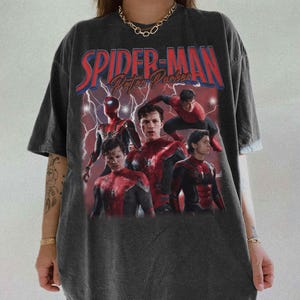 May include: Dark grey t-shirt with a graphic of Spider-Man and the text "Spider-Man Peter Parker" in red and blue. The graphic shows multiple images of Spider-Man in his suit against a red lightning background.