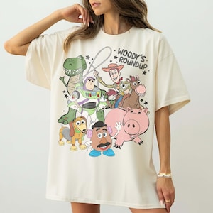 May include: A white ceramic mug with a black handle and the text "But First, Coffee" in a black, handwritten-style font. The mug is on a white surface.