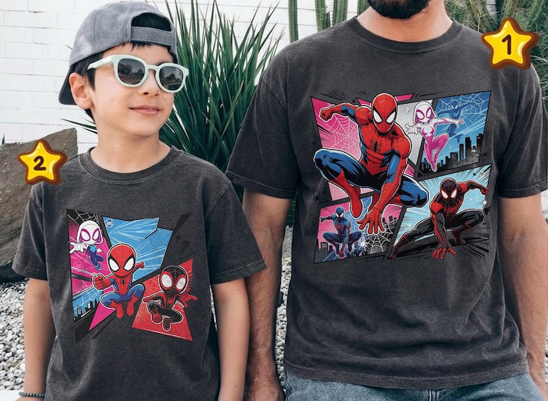 K&ouml;nnte beinhalten: Zwei anthrazitfarbene T-Shirts mit einer Comic-Grafik von Spider-Man und anderen Spider-Verse-Charakteren. Die Shirts werden von einem Kind und einem Erwachsenen getragen, was auf ein passendes Set hindeutet.