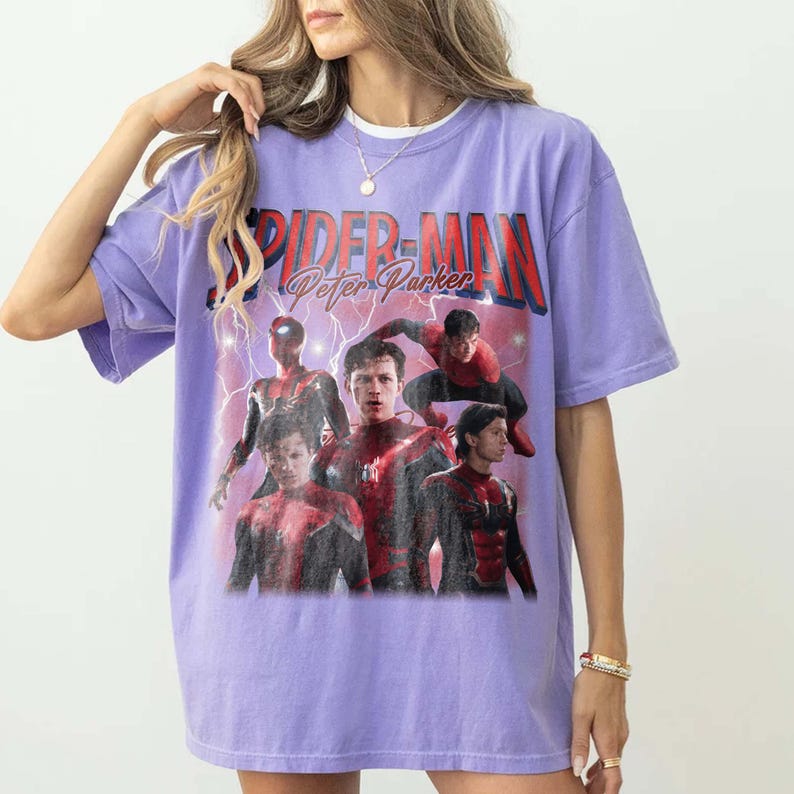 May include: A lilac t-shirt with a graphic of Spider-Man and the text "SPIDER-MAN Peter Parker" in red and white. The design features multiple images of Spider-Man in action poses, with lightning effects.