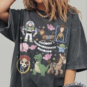 Pu&ograve; includere: T-shirt grigio scuro con una grafica colorata dei personaggi di Toy Story, tra cui Buzz Lightyear, Woody e Rex. &Egrave; presente anche la frase "You've Got a Friend in Me". La maglietta &egrave; Comfort Colors Pepper.