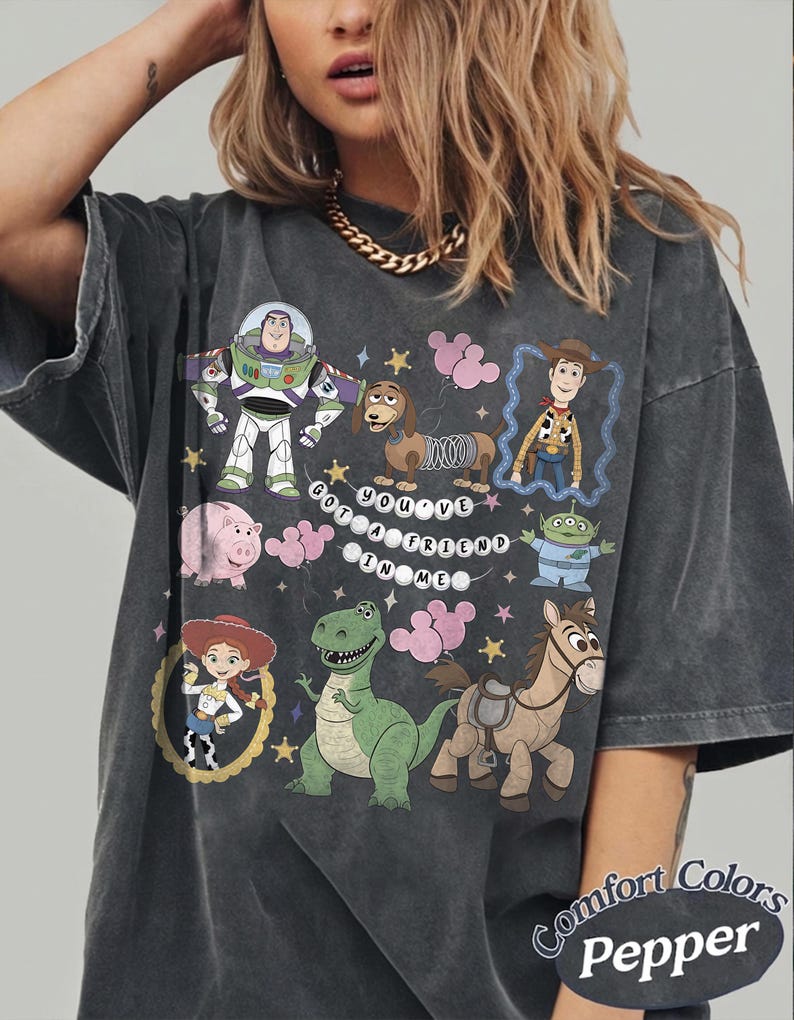 Pu&ograve; includere: T-shirt grigio scuro con una grafica colorata dei personaggi di Toy Story, tra cui Buzz Lightyear, Woody e Rex. &Egrave; presente anche la frase "You've Got a Friend in Me". La maglietta &egrave; Comfort Colors Pepper.