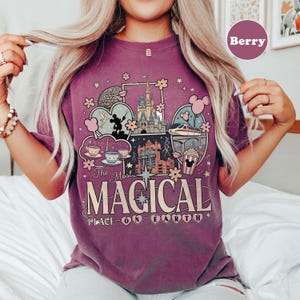Puede incluir: Camiseta color bayas con un dise&ntilde;o gr&aacute;fico que muestra im&aacute;genes ic&oacute;nicas de parques tem&aacute;ticos, como un castillo, tazas de t&eacute; y un monorra&iacute;l. El texto "The Most Magical Place on Earth" se muestra de forma destacada. La camiseta es informal y c&oacute;moda.