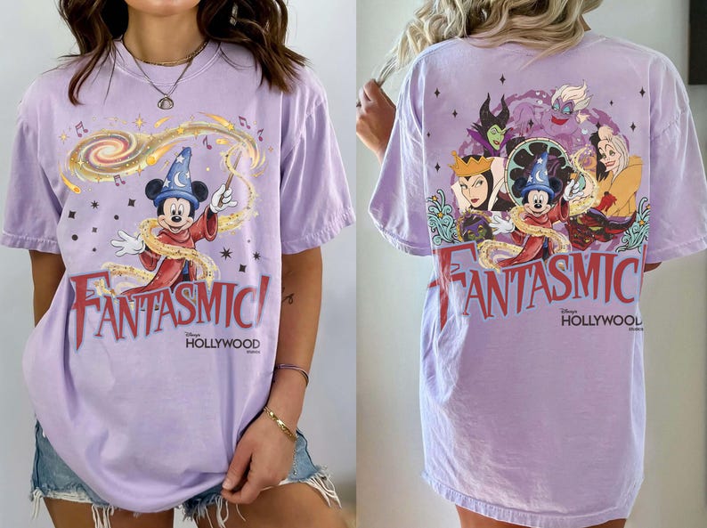 May include: A light purple t-shirt featuring Mickey Mouse as the Sorcerer's Apprentice with the text "FANTASMIC!" in red. The back of the shirt shows Disney villains. The shirt is a relaxed fit.