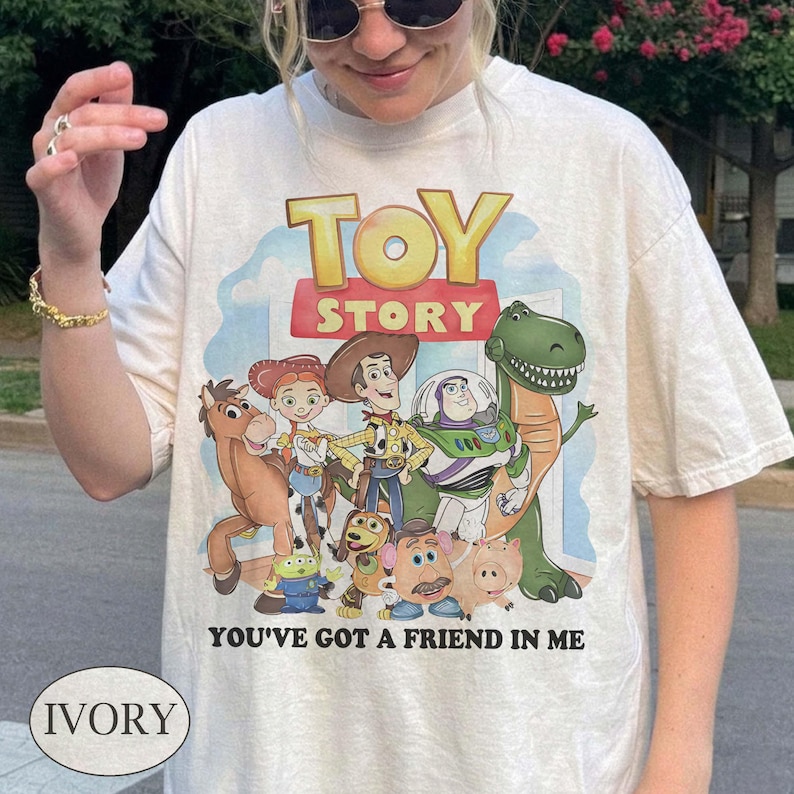 Puede incluir: Camiseta de color marfil con un gr&aacute;fico colorido de personajes de la pel&iacute;cula animada "Toy Story". El dise&ntilde;o incluye el t&iacute;tulo de la pel&iacute;cula y la frase "You've Got a Friend in Me".