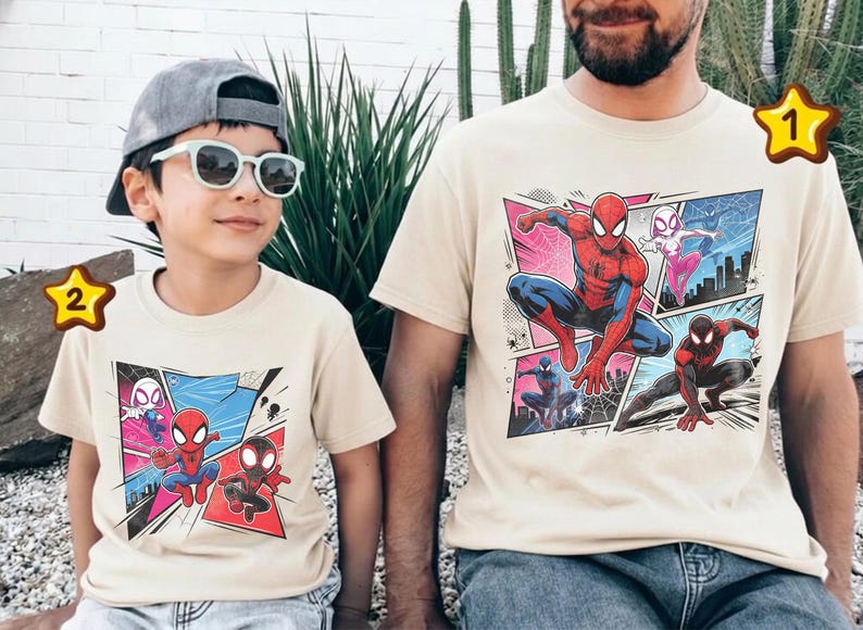 K&ouml;nnte beinhalten: Beige T-Shirts mit einem Comic-Grafik-Stil von Spider-Man und anderen Charakteren. Die Shirts werden von einem Kind und einem Erwachsenen getragen. Die Grafik zeigt Spider-Man in verschiedenen Posen mit einem Stadtlandschaftshintergrund.