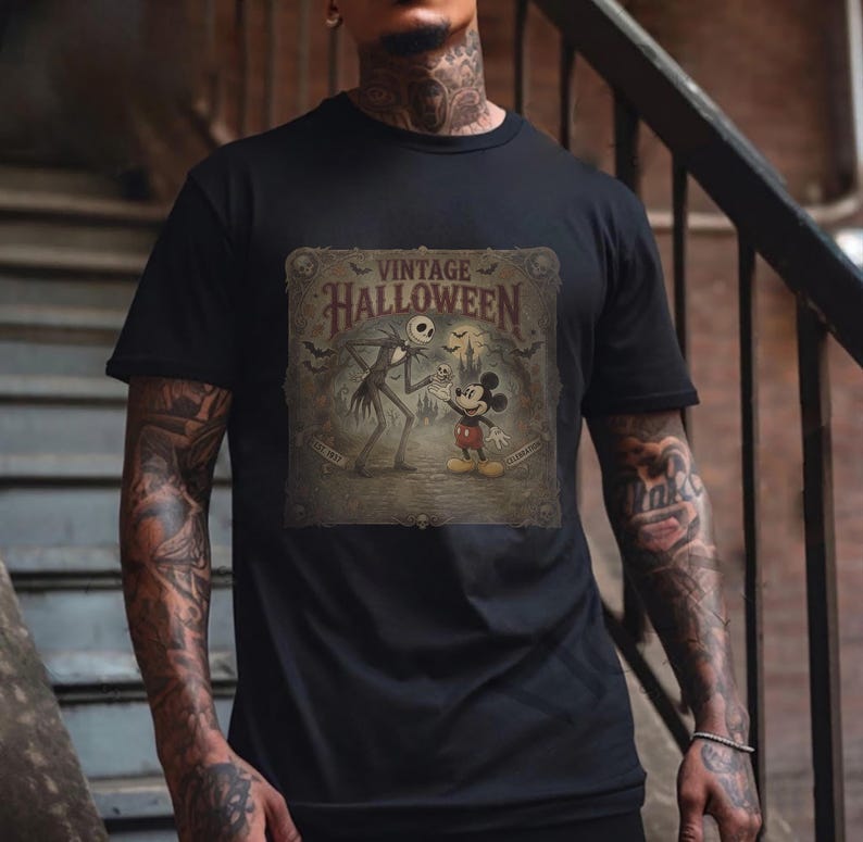 May include: A black short-sleeve t-shirt featuring a graphic print with the text VINTAGE HALLOWEEN. The design depicts a tall skeletal figure and a cartoon mouse character standing in front of a castle silhouette with bats in a sepia-toned frame.