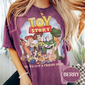 Puede incluir: Camiseta color bayas con un gr&aacute;fico de personajes de la pel&iacute;cula animada "Toy Story". El dise&ntilde;o incluye a Woody, Buzz Lightyear y otros personajes, con el texto "TOY STORY" y "YOU'VE GOT A FRIEND IN ME."