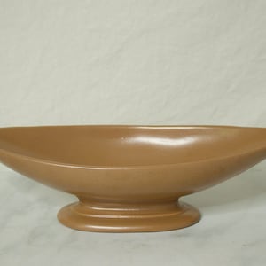 Może przedstawiać: Brązowa ceramiczna miska o szerokim, owalnym kształcie i podstawie na nóżce.