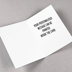 May include: An open white greeting card with black text that reads, "YOUR PERSONALISED MESSAGE CAN BE PRINTED INSIDE THE CARD." The card is on a light gray surface.