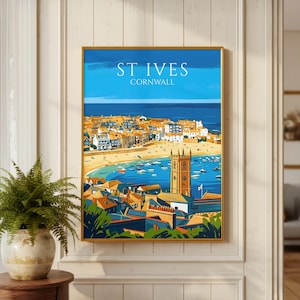 May include: A framed travel poster print of St. Ives, Cornwall, featuring a coastal town with orange-roofed buildings, a sandy beach, a blue harbor filled with boats, and a tall stone church tower under a bright blue sky with white text.